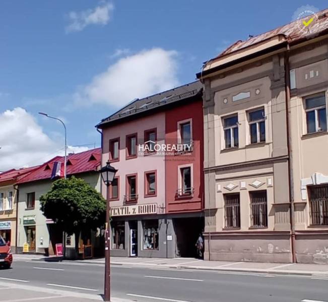 Commercial spaces in Brezno with colorful historical facades and parked cars.