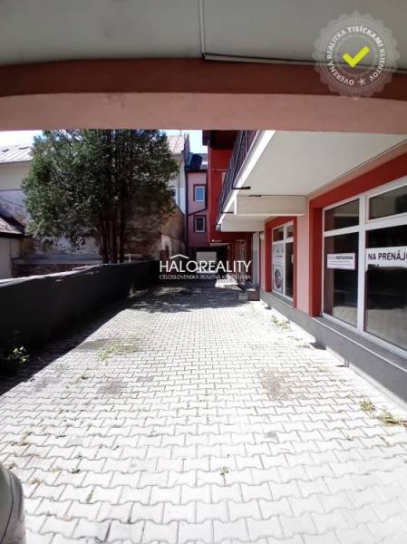 Commercial premises in Brezno with a paved sidewalk and trees in the background.