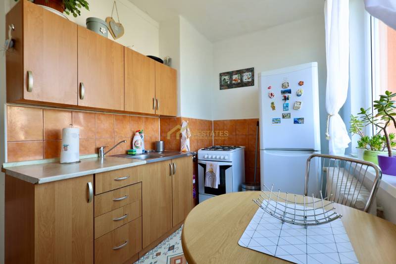 Kitchen in a 2-room apartment with wooden cabinets, appliances, and decorations.