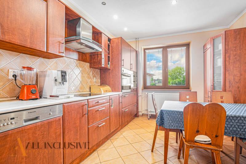 A kitchen in a family house with wooden furniture, appliances, and a dining table.