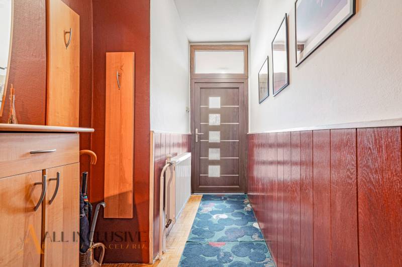 A hallway in a family house with wooden paneling, a coat rack, and doors with frosted glass.