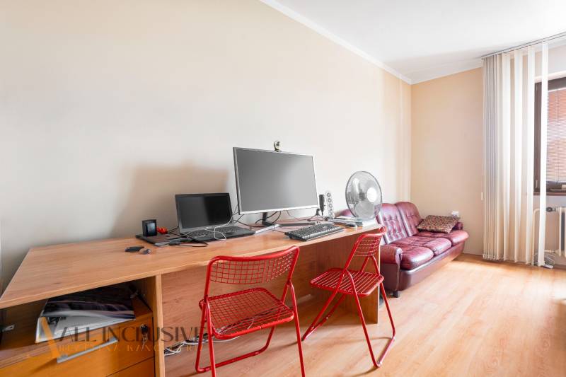 A desk with red chairs and a computer in a family house.