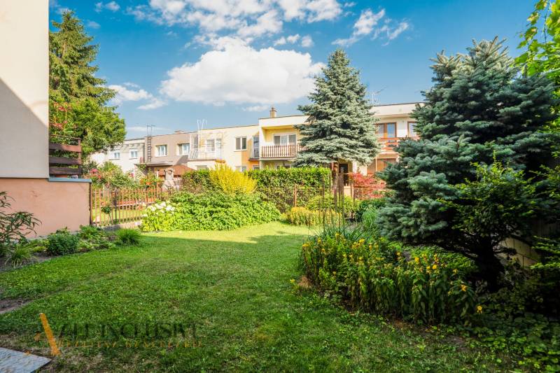 In the garden of a family house in Dunajská Streda, there are trees, flowers, and a lawn.
