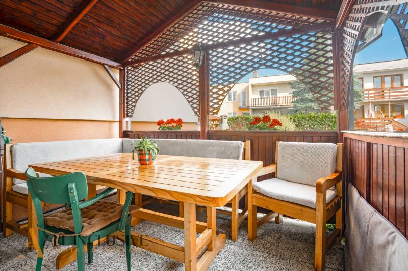 The terrace of a family house in Dunajská Streda with wooden seating and flowers.