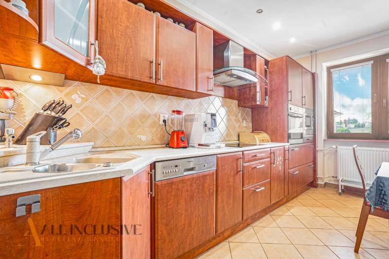 A kitchen with wooden cabinets, a ceramic sink, and appliances in a family house.