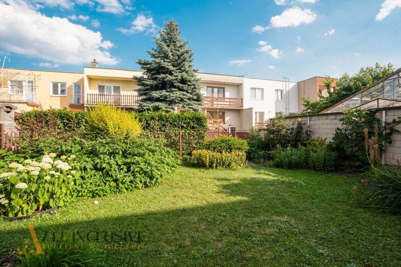 A garden of a family house in Dunajská Streda with a large tree and flowers.