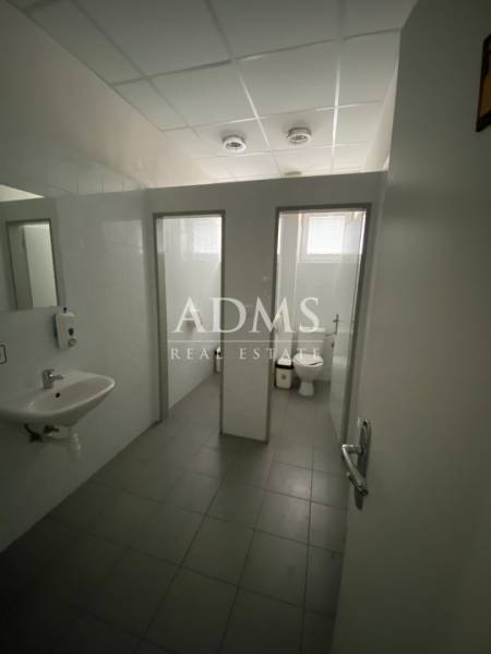 Toilets in warehouses and halls with a sink and two stalls.