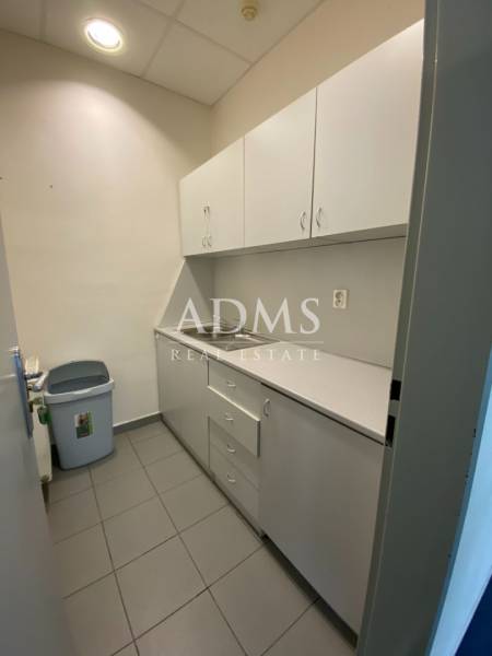Kitchen corner in a warehouse with white cabinets and a sink.