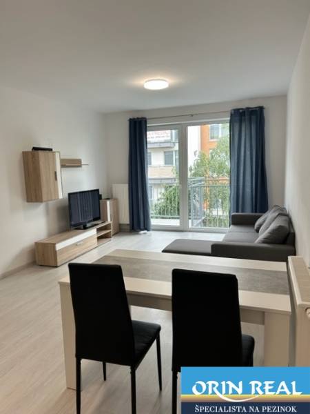 Living area with a sofa in a 2-room apartment, bright interior with a TV and a balcony.