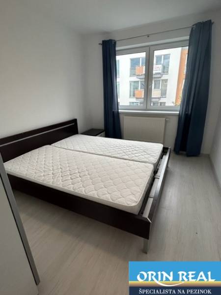 Bedroom in a 2-room apartment with a double bed and a window, blue curtains.