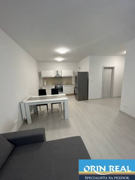 Living room with kitchen in a 2-room apartment, white furniture, gray sofa, dining table.