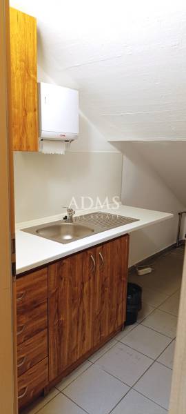 An office with a sink, cabinets, and a trash can for practical dishwashing.