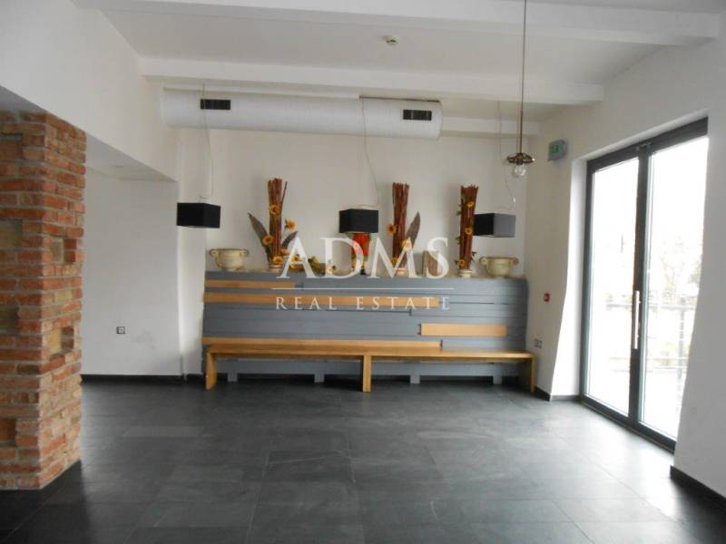 Interior of commercial spaces with decorative vases and a large window on the right side.