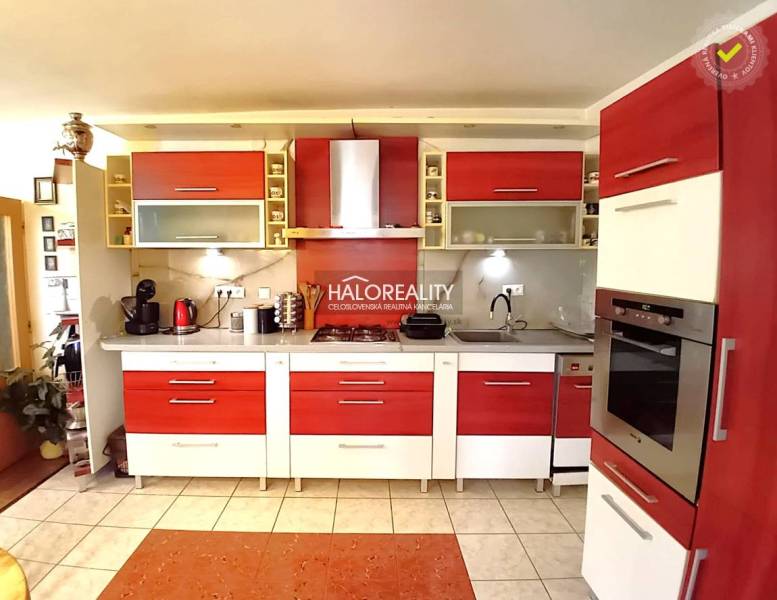 A kitchen with red and white elements in a family house, equipped with appliances and cabinets.