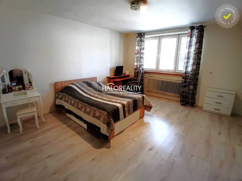 A room in a family house with a bed, a table, and a window with a view outside.