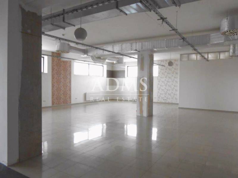 Empty commercial spaces with large windows and columns, suitable for various uses.