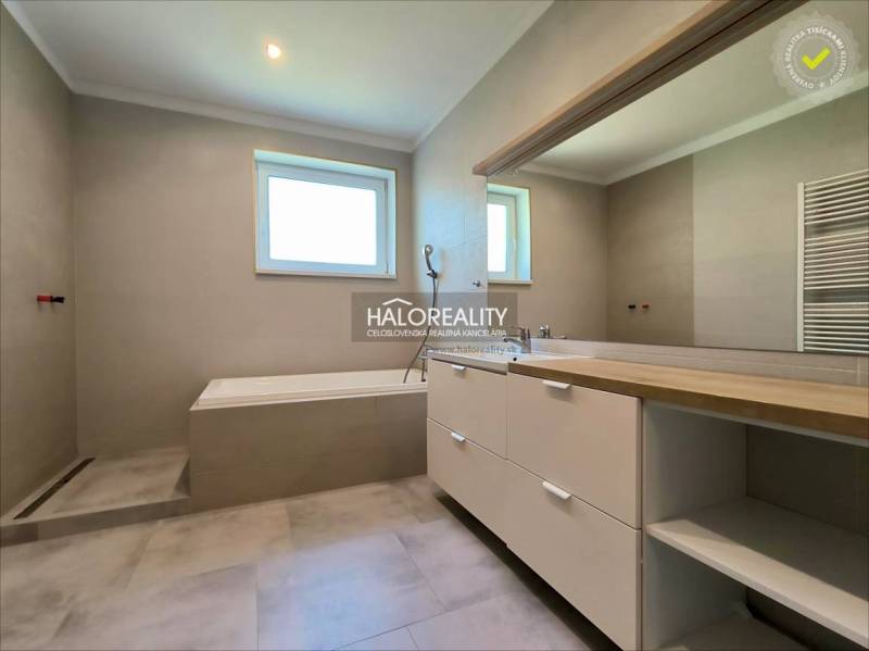 A bathroom in a family house with a bathtub and a large mirror, neutral shades.