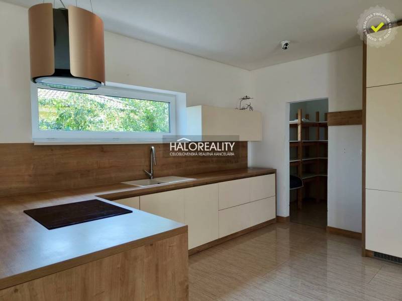 A kitchen in a family house with wooden cabinets and a large window.
