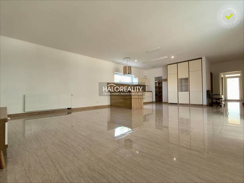 Spacious living room with a glossy floor, built-in wardrobe, and kitchenette in a family house.