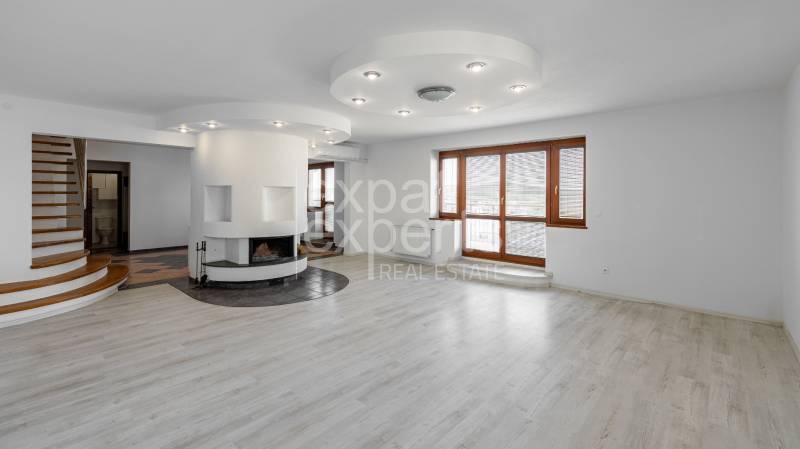 A spacious living room in a 5 or more bedroom apartment with a fireplace and staircase.