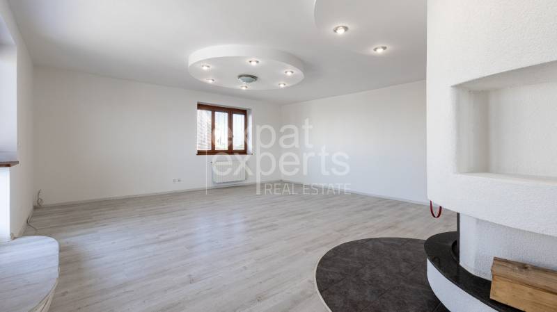 A spacious room with white walls and wooden flooring in a 5 or more room apartment.
