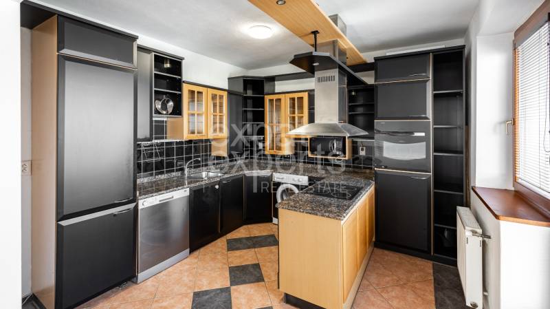 A kitchen in a 4-room apartment with dark cabinets and appliances, a sunny window on the right.
