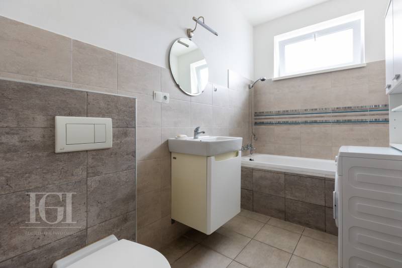 Bathroom in a 2-room apartment with a shower, sink, and washing machine.