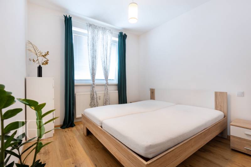 A bright bedroom with a wooden bed and nightstands in a two-room apartment.