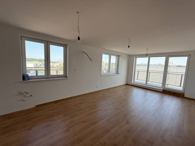 A spacious room with large windows and laminate flooring in a 2-room apartment.