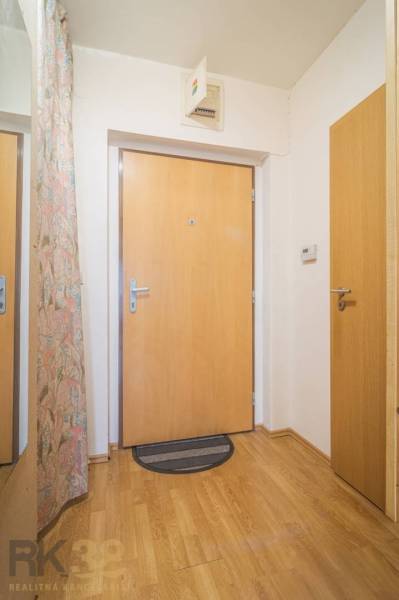 A balcony of a 3-room apartment with a view of a quiet street and greenery in Poprad.