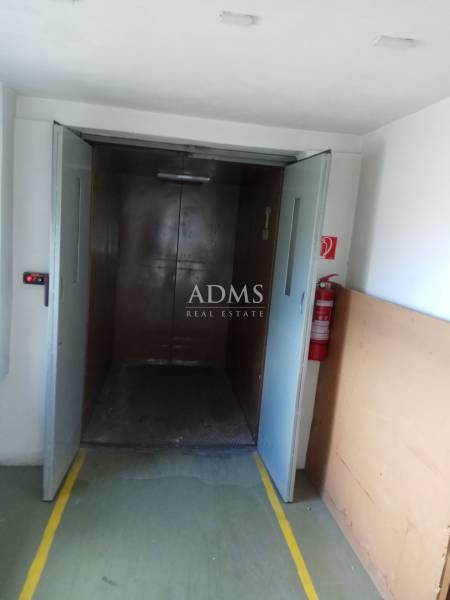 A large elevator opening in a manufacturing area with a fire extinguisher on the wall.