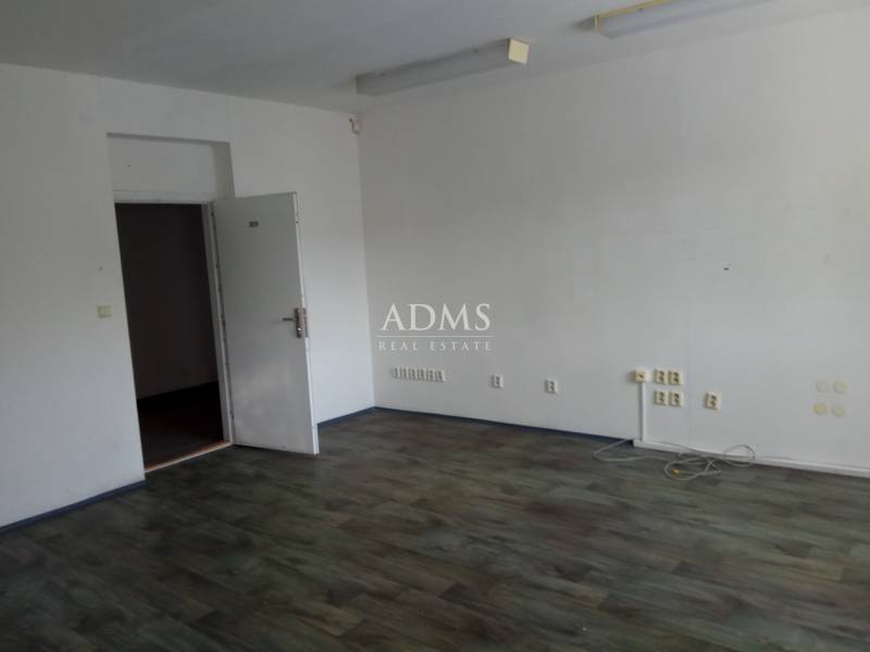 An empty interior of a manufacturing space with wooden flooring and open doors.