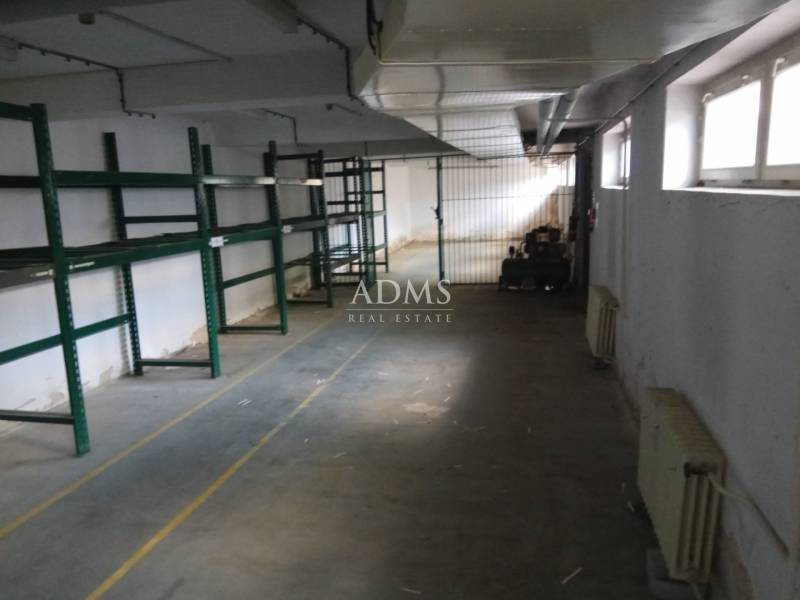 Empty manufacturing space with green metal shelves and windows on one side.