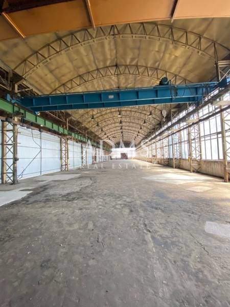 Interior of a warehouse and hall with an overhead crane and a high arched ceiling.