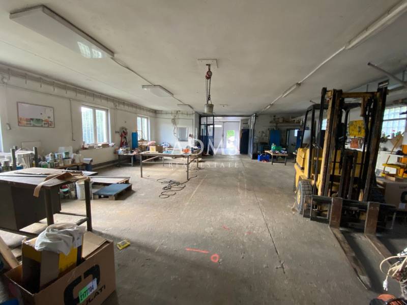 Interior of a warehouse and hall with workbenches and a forklift in the corner of the room.