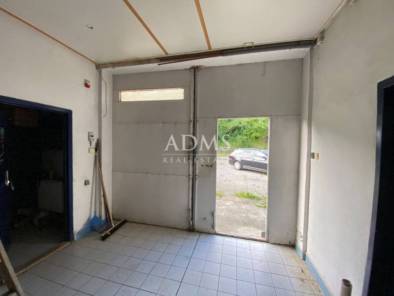 Interiors of warehouses and halls with open doors and a view of a car outside.
