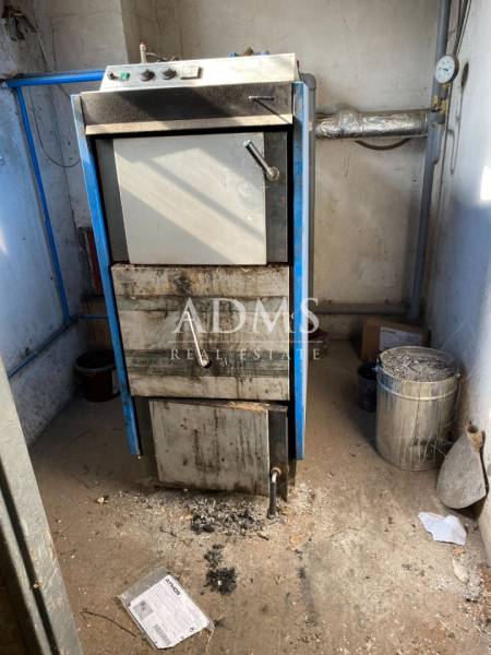 An industrial boiler in a boiler room of warehouses and halls with ash on the ground.