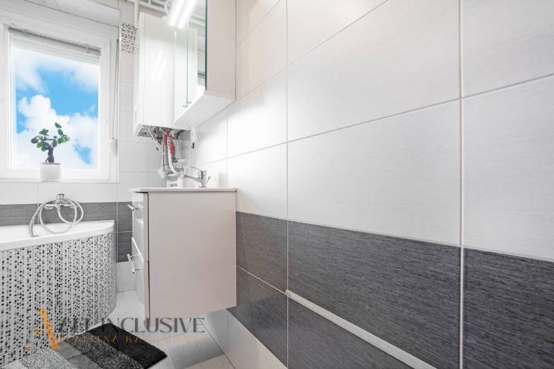 A bathroom in a 2-room apartment with a combination of white and gray tiles.