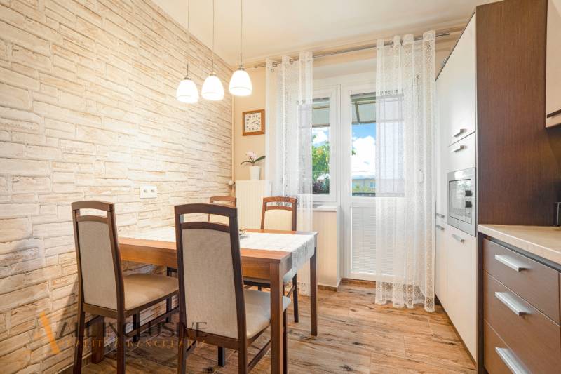 Dining area with a wooden table and chairs in a 2-room apartment, decorated with brick cladding.