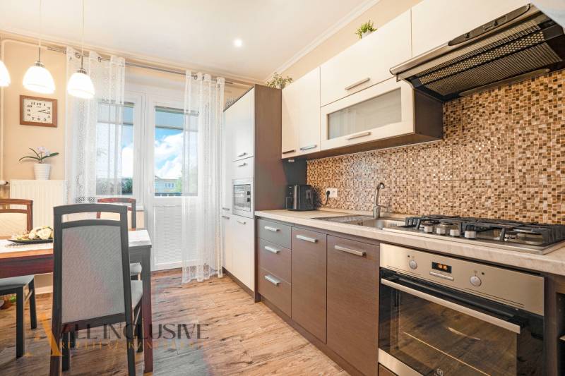 A kitchen in a 2-room apartment with a dining table and a cooktop.