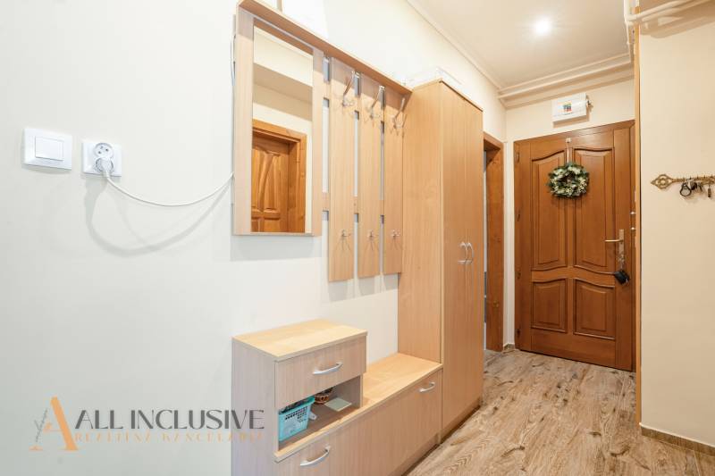 The entrance hall of a 2-room apartment with wooden furniture, a mirror, and wall hooks.