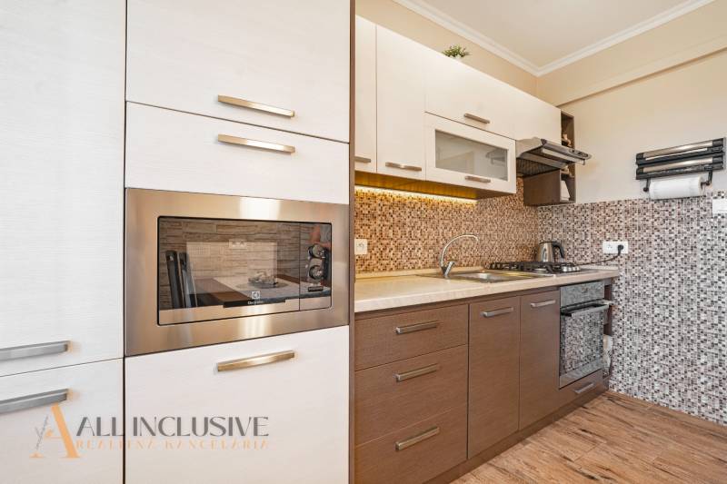 Modern kitchen in a 2-room apartment with wooden flooring and built-in appliances.