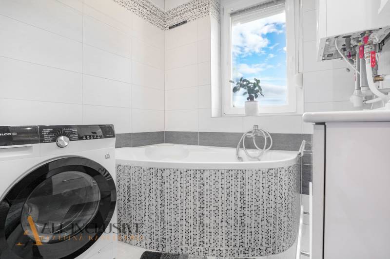 Bathroom in a 2-room apartment with a bathtub and a washing machine, bright space with a mirror.