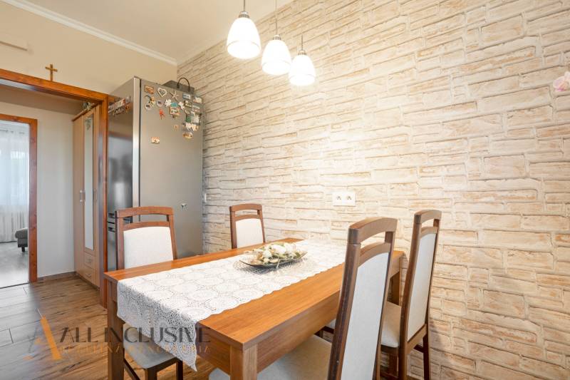 Dining room in a 2-room apartment with a wooden table and brick wall cladding.
