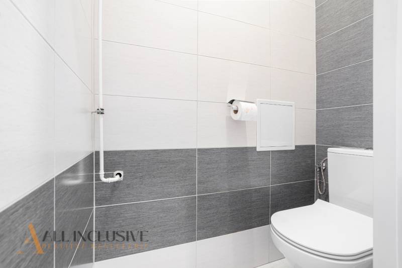 A bathroom in a 2-room apartment with tiles in white and gray shades.