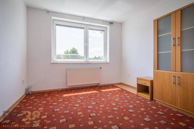 A room in a 3-room apartment with a window, a carpet, and a cabinet.