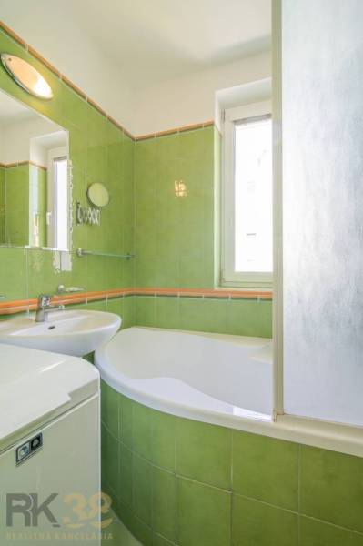 A bathroom with green tiles and a bathtub in a 3-room apartment.