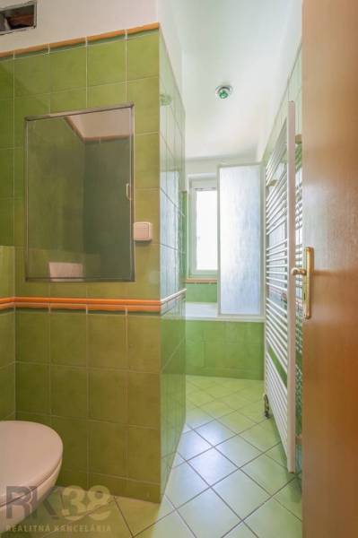 A bathroom with green tiles and a bathtub in a 3-room apartment.