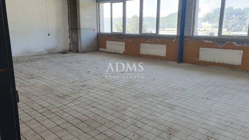 Empty room with tiles, large windows, and a view of the industrial area.