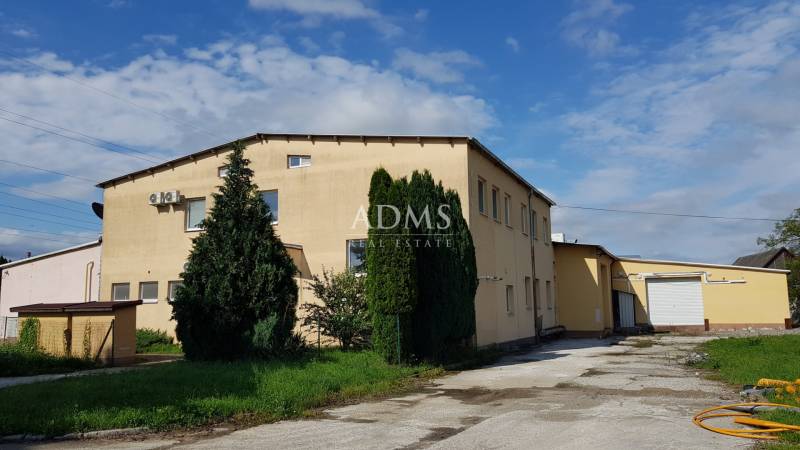 Warehouses and halls on Kpt. Nálepku Street in Ilava, a building surrounded by trees and grass.